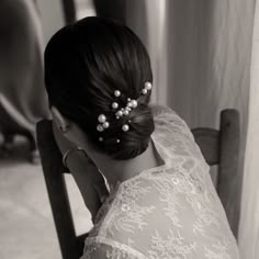 a woman sitting in a chair wearing a wedding dress with pearls on her head and hair comb