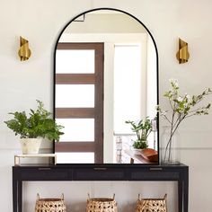 a console table with two chairs and a mirror on it, in front of a doorway