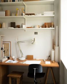 a desk with a lamp, bookshelf and other items on the shelves above it