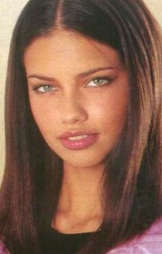 a young woman with long brown hair and blue eyes is posing for the camera, wearing a pink jacket