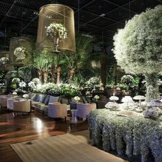 a room filled with lots of tables and chairs covered in flowers, plants and greenery