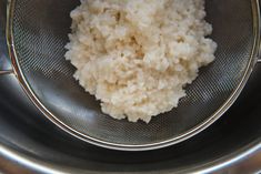 rice in a strainer bowl on top of a stove