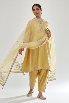 Yellow silk chanderi short kalidar kurta with zari bootis, dori embroidered neckline and contrast bead work. Paired with narrow salwar in dori, zari and gota flower embroidered bootas and dupatta.
Components: 3
Pattern: Embroidery
Type Of Work: Zari, dori, gota, aari, bead
Neckline: Notched
Sleeve Type: Three quarter
Fabric: Kurta and Salwar: Silk Chanderi, Dupatta: Silk Organza
Color: Yellow
Other Details: 
Gota lace embroidered border
Side pockets
Elasticated back
Tassel bordered sheer dupatta Suit Inspo Women, Plain Suits, Kurta Embroidery, Kalidar Kurta, Sheer Dupatta, Yellow Kurta, Chanderi Dupatta, Traditional Attires, Kurti Set