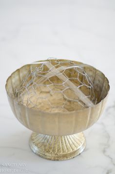 a metal bowl sitting on top of a white counter next to a marble tablecloth