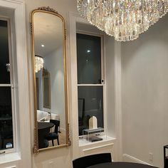 a dining room table with chairs and a chandelier hanging from it's ceiling