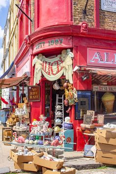 a red store front with lots of boxes on the sidewalk and other items outside it