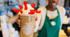 a woman holding up a starbucks drink with whipped cream and strawberries on the top