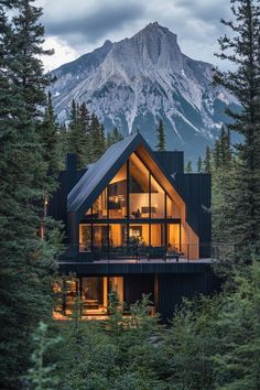 a house in the woods with mountains in the background at night, surrounded by trees and evergreens