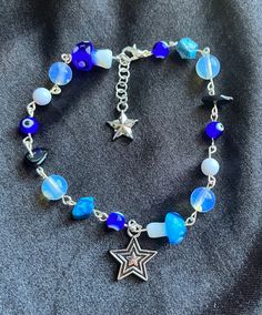 Blue beaded silver charm bracelet with stars, beads, beaded rocks, and evil eyes. Blue Star Jewelry, Beaded Charm Bracelet For Festivals With Round Beads, Silver Beaded Star Bracelets, Blue Dangle Bracelets With Charms, Silver Beaded Bracelets With Star Charm, Silver Beaded Bracelet With Star Charm And Round Beads, Spiritual Beaded Charm Bracelet For Festivals, Blue Beaded Bracelets With Star Charm For Gift, Blue Beaded Bracelets With Silver Beads For Festivals