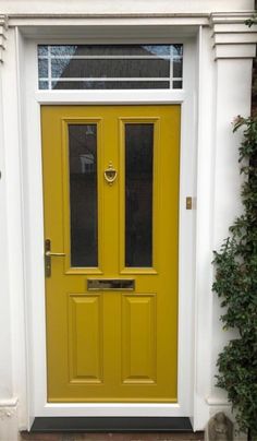 a yellow front door with two sidelights and glass panels on the top part of it