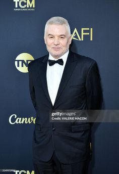 an older man in a tuxedo and bow tie standing on the red carpet