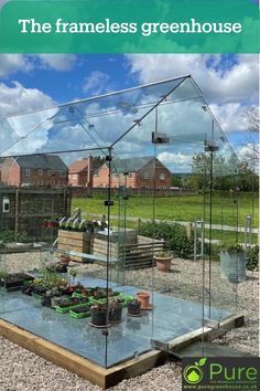 a glass house sitting on top of a gravel ground next to a garden filled with potted plants