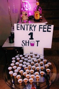 there is a sign that says entry fee 1 shot on the table with cups in front of it