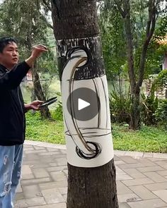 a man standing next to a tree with an electric cord attached to it's trunk