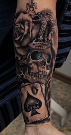 a man's arm with a skull and crown tattoo design on the left forearm