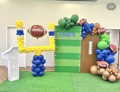 balloons and footballs decorate the entrance to a sports themed event at an office building