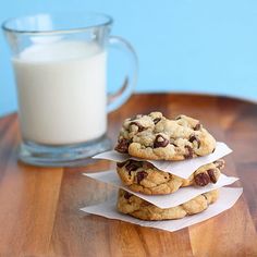 three chocolate chip cookies stacked on top of each other next to a glass of milk