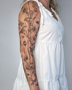 a woman wearing a white dress with tattoos on her arm