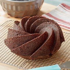 a chocolate bundt cake sitting on top of a cooling rack next to a knife