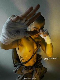 a man with no shirt on holding his hand up to his face while wearing boxing gloves