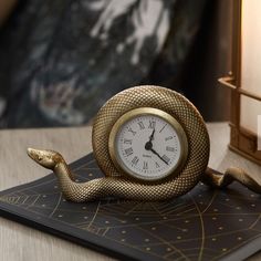 a clock sitting on top of a table next to a snake