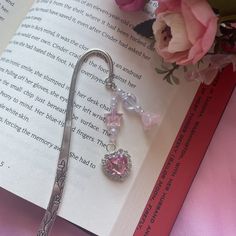 a bookmark with a pink crystal heart on it next to some flowers and a flower pot