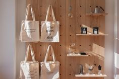 three totes hanging on the wall in front of shelves with books and other items