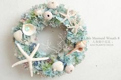 a wreath with seashells, starfish and shells hanging on the side of a wall