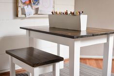 a white table with two benches and a laptop on it, in front of a window