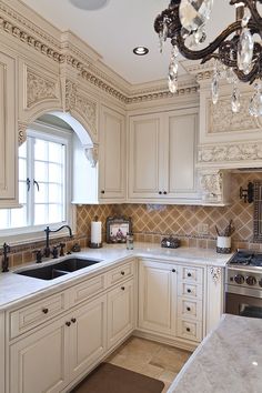 an elegant kitchen with white cabinets and marble counter tops, chandelier hanging from the ceiling