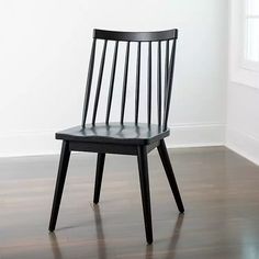 a black wooden chair sitting on top of a hard wood floor next to a window