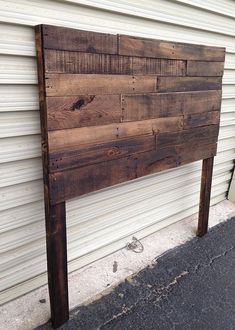 a wooden sign sitting on the side of a building next to a garage door,