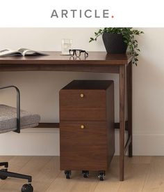 a desk with a chair and a book on it next to a potted plant