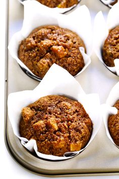 several muffins in paper cups sitting on top of a metal baking pan with white napkins