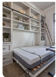 a bed with a mattress on top of it in front of a bookcase and window