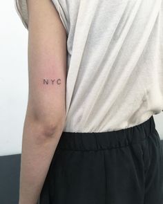 a woman's arm with the word nyc tattooed on her left side, in black ink