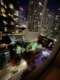 cityscape at night with buildings and pool in foreground, seen from window