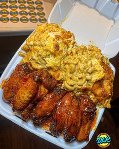 chicken wings with macaroni and cheese in a foam container on top of a table