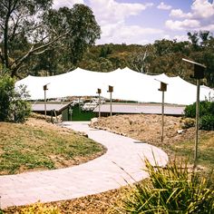 a white tent is set up in the middle of a grassy area