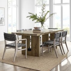 a dining room table with chairs around it and a vase on top of the table