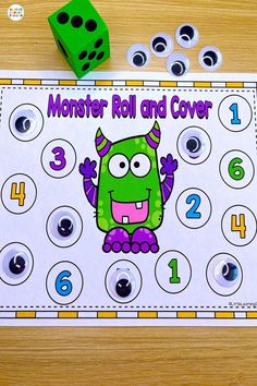 a monster roll and cover game on a table with dices next to the board