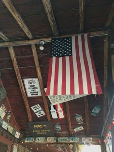 an american flag hanging from the ceiling of a building with signs and other items on it