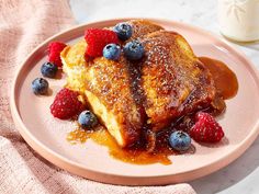 french toast with berries and syrup on a pink plate