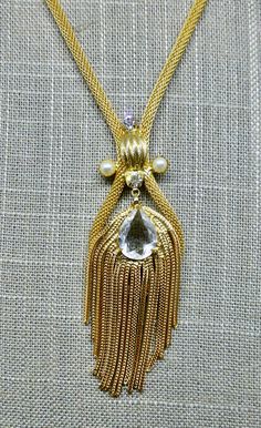 This stunning necklace looks like it could have been made by Hobe or Napier but there is no makers mark.  This very glam necklace looks like it has never been worn, it's in excellent condition. The mesh chain is fashioned into a loop at the bottom and the tassel rests on it.  The tassel has been set with a clear pear shaped stone.  The tassel moves independently so it has a lot of movement.  It is also set with 2 white faux pearls and 2 other small clear stones.   The chain part of the necklace Evening Costume Jewelry Necklace With Chain, Evening Costume Jewelry With Chain Detail, Evening Costume Jewelry With Chain, Evening Costume Jewelry Chain, Evening Pendant Necklace With Chain Detail, Costume Jewelry Pendant Chain Necklace For Parties, Evening Pendant Necklace With Chain, Evening Metal Necklace With Gold Chain, Evening Costume Jewelry Dangle Necklaces