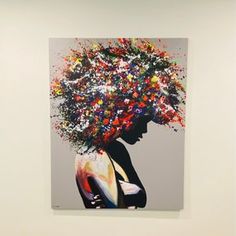 a woman's head is covered with multicolored flowers in an art gallery