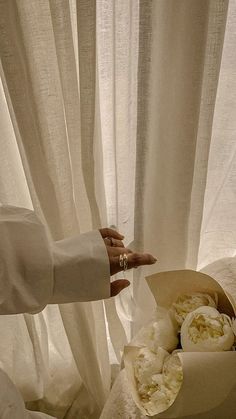 a person reaching for something in a box on a bed with white curtains behind them