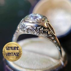 an antique style engagement ring with a diamond in the center and engraved on the side