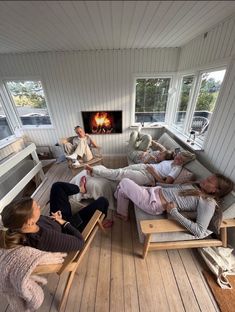 four people laying on couches in front of a fire place