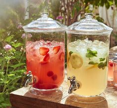 two jars filled with drinks sitting on top of a wooden table next to each other