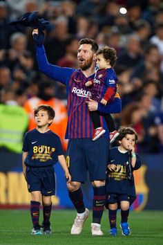 a soccer player is holding his son's hand as he walks on the field